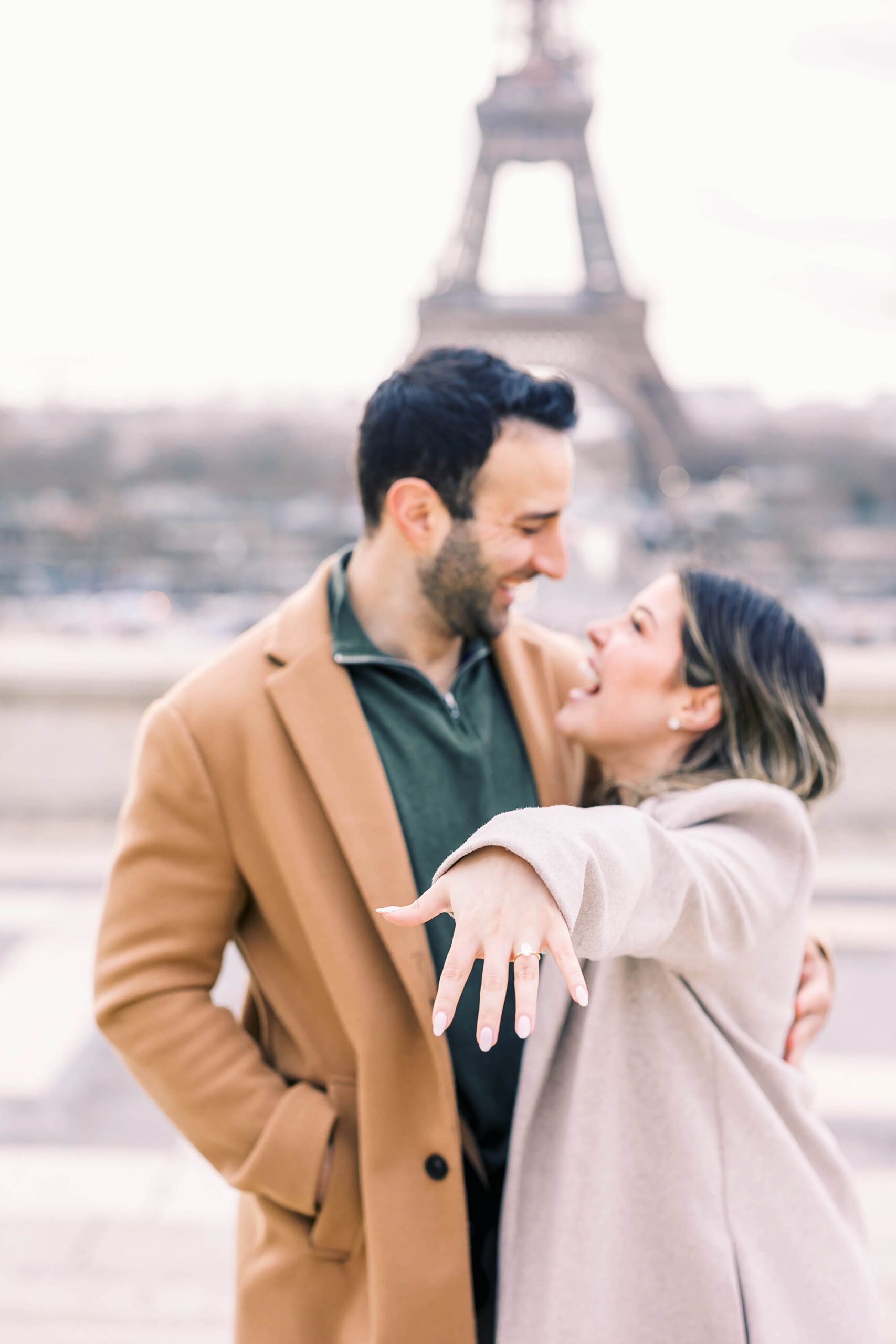 girl showing off diamond engagement ring in front of the eiffel tower in paris