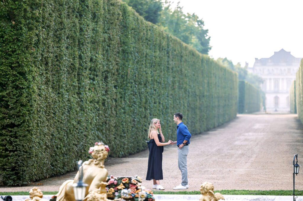a man about to get down on one knee to propose to his girlfriend at the palace of versailles