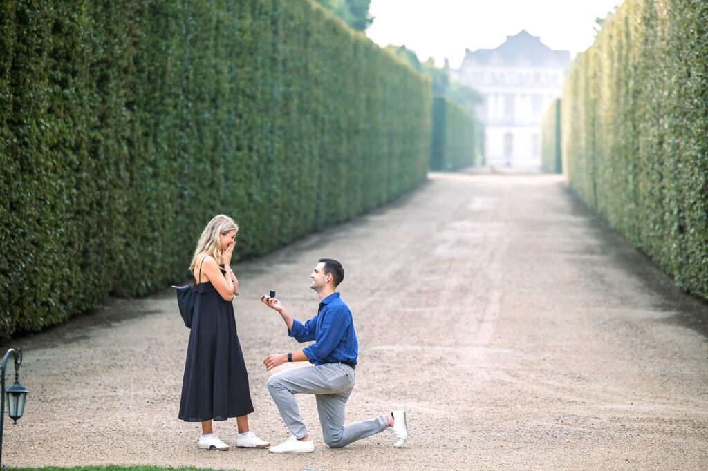 a guy proposing to his girlfriend in the gardens of versailles