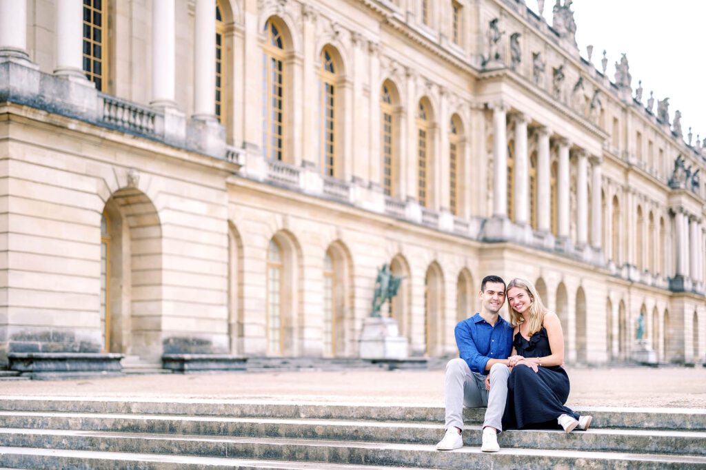 couple sitting together in the gardens of versailles after getting engaged