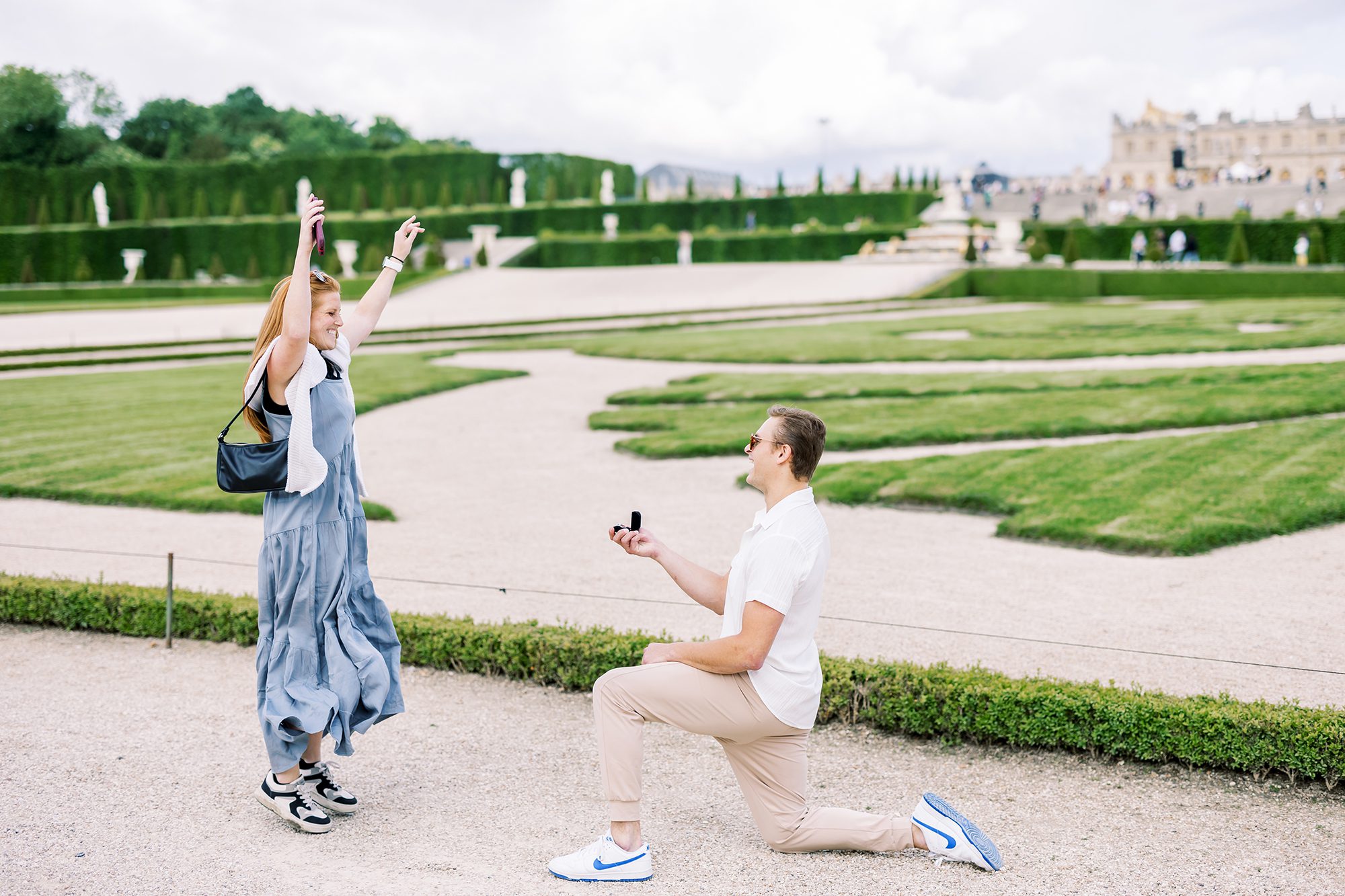 excited girl jumping after being proposed to in the gardens of versailles