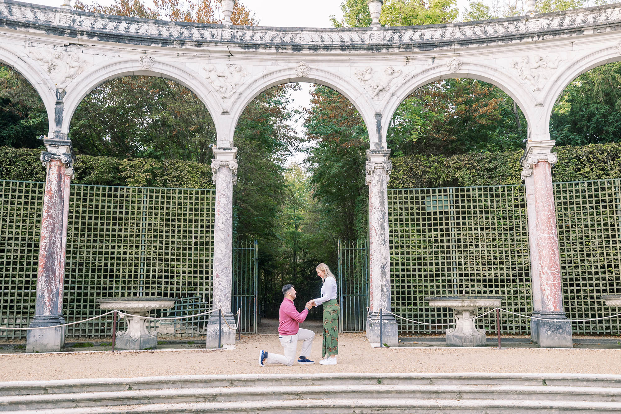a guy proposing to his girlfriend at the palace of versailles gardens